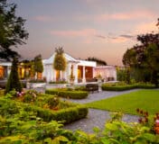 Elegant hotel gardens at sunset with gazebo, lush greenery, vibrant flowers, and inviting patios.