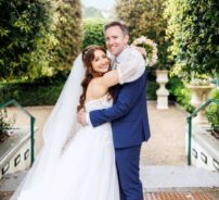 Happy couple embraces in lush garden setting of luxury hotel, ideal for weddings and romantic getaways.