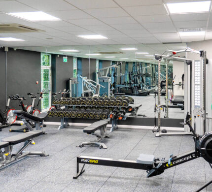 Modern hotel gym with sleek equipment, weights, and cycling machines, ideal for fitness-focused guests.