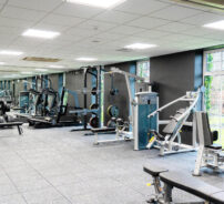 Modern hotel gym with state-of-the-art equipment and large windows offering garden views for an invigorating workout.