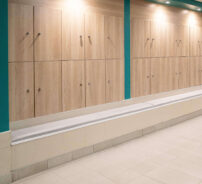Elegant wooden lockers with cushioned seating in modern hotel changing room, offering comfort and convenience.