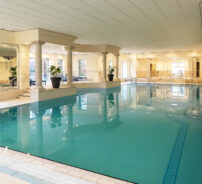 Luxurious indoor swimming pool with elegant pillars and natural light for relaxation at the hotel.