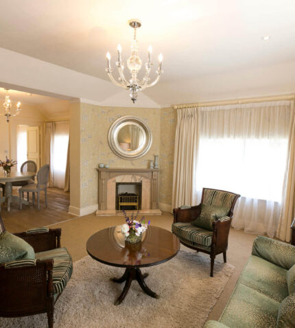 Elegant hotel suite with plush seating, chandelier, and dining area, providing luxurious comfort and style.